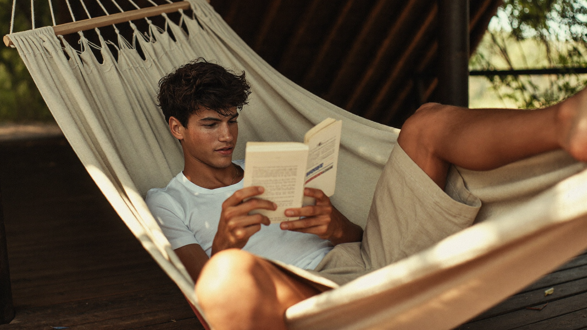 Homem relaxando na rede em leitura no chalé